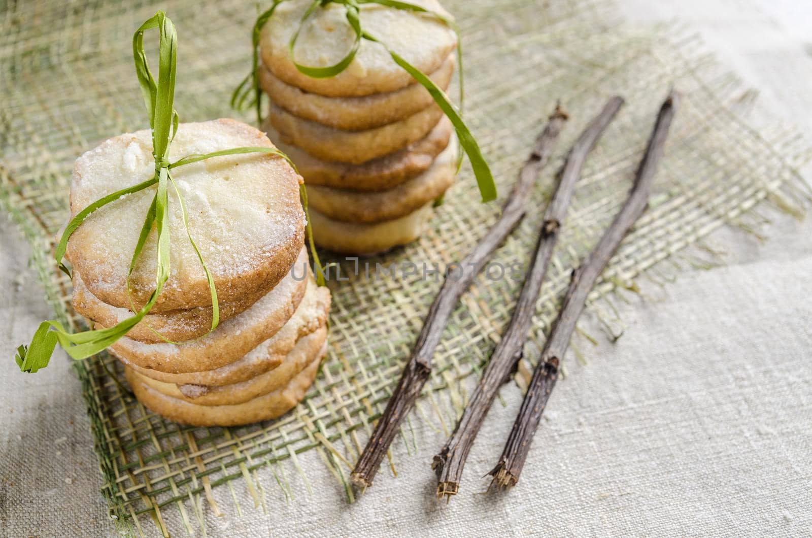 Homemade lemon sugar cookies tied up with rope and dried branches on linen tablecloth, blurred background From series Winter pastry