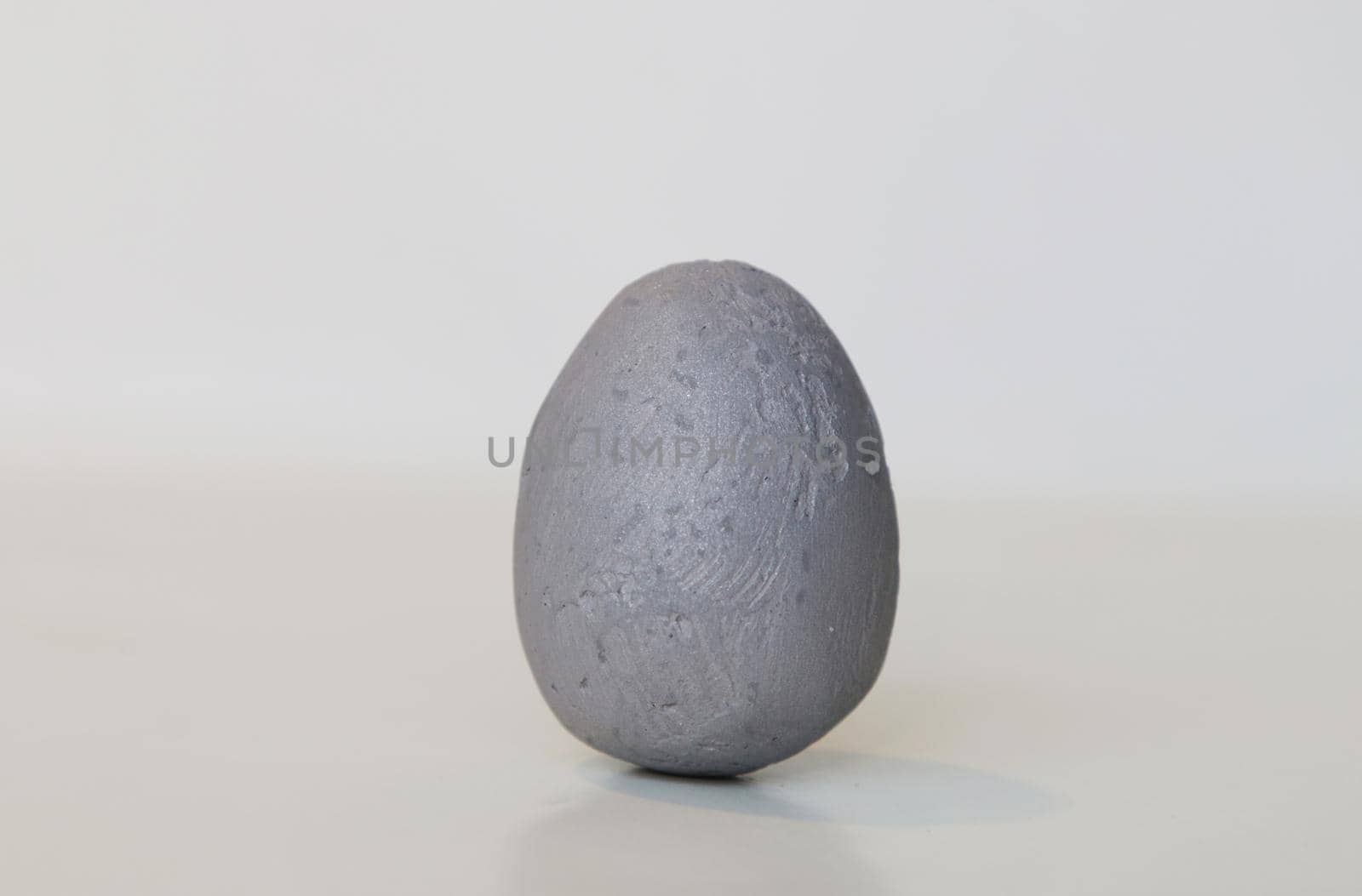 Artificial gray egg on light background. Abstract image of a stone egg.