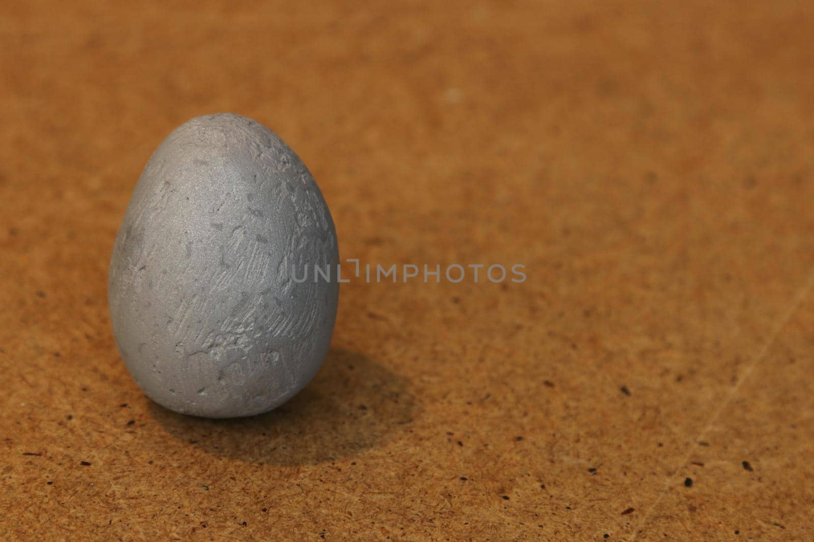 Artificial stone egg on a brown wooden background.