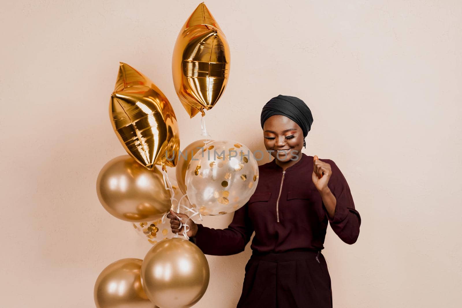 Muslim new year party with golden balloons for black woman. African attractive girl celebration of the end of year. Happy emotion