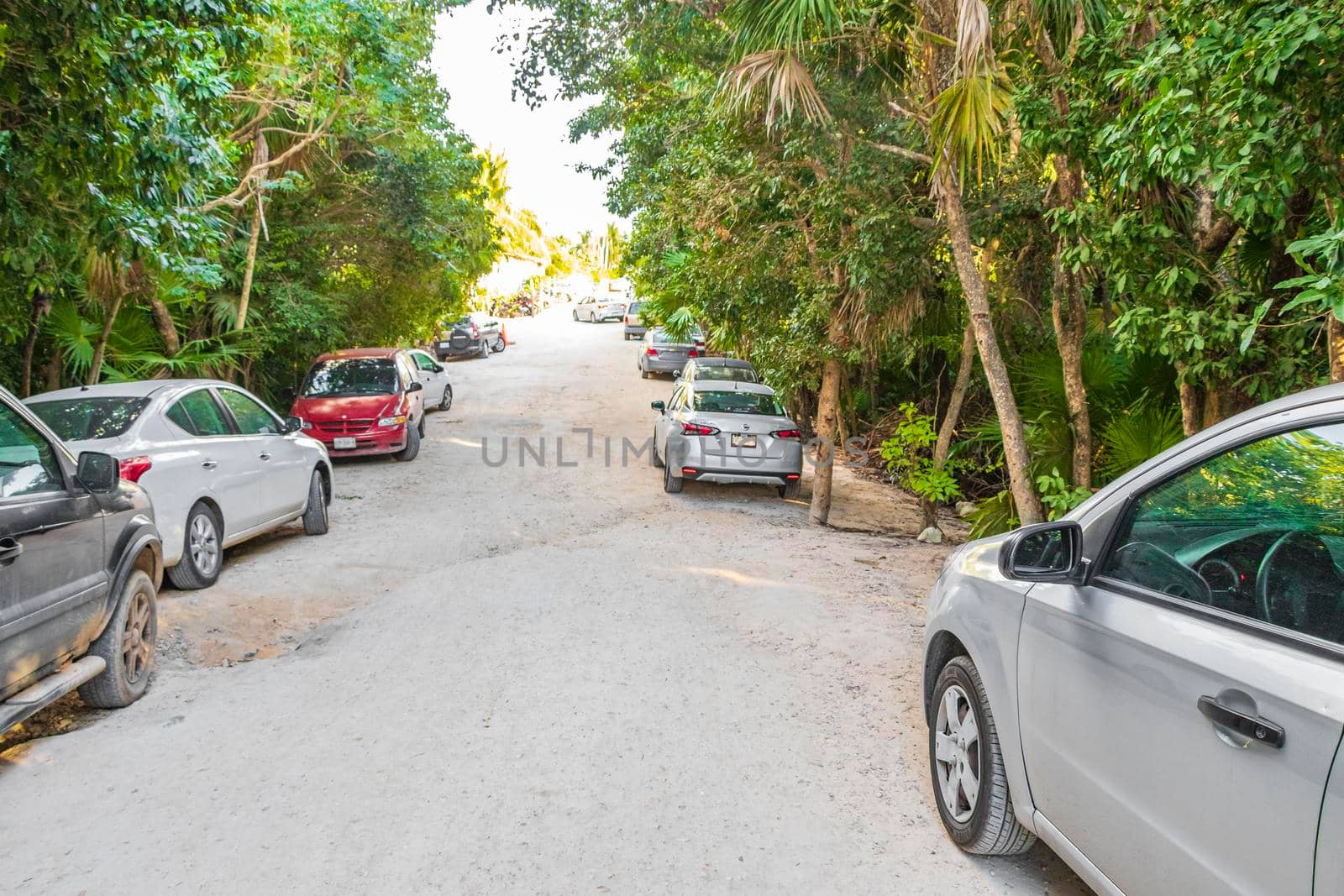 Tulum Mexico 02. February 2022 Sandy way path entrance to the amazing and beautiful caribbean coast and beach with panorama view turquoise water people and parked cars of Tulum in Quintana Roo Mexico.