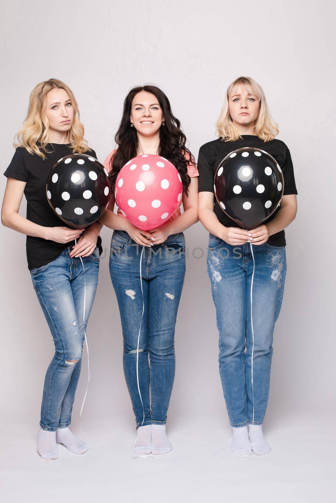 Three female friends celebrating a party event having fun and smiling with balloons