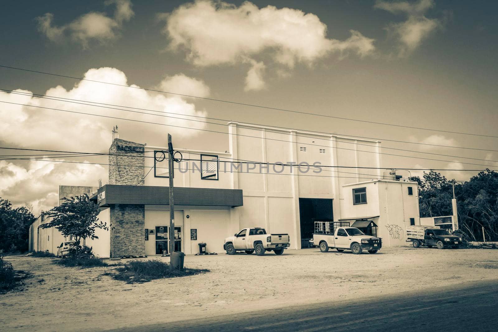 Tulum Mexico 02. February 2022 Old black and white picture of driving thru typical colorful street road and cityscape with cars traffic palm trees bars and restaurants of Tulum in Mexico.