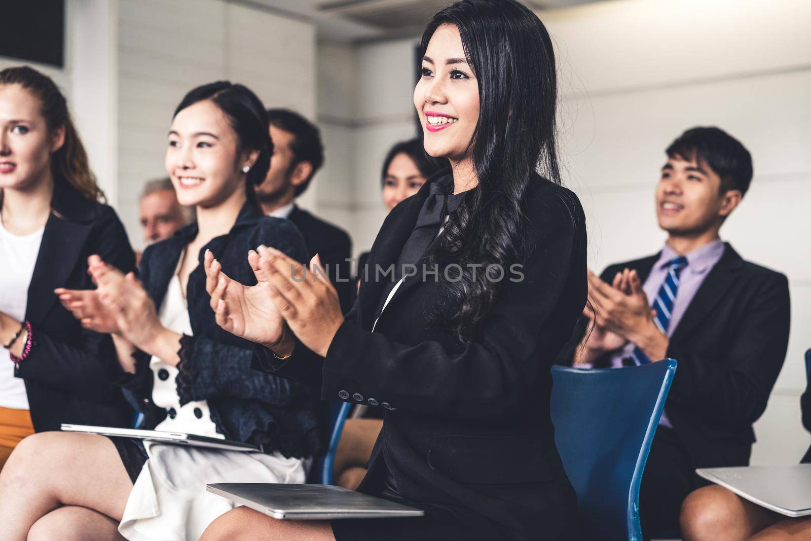 Professional young Asian and Caucasian audience applauding in group meeting presentation from the partnership at the office. Businessmen and businesswomen celebrating the great success achievement.