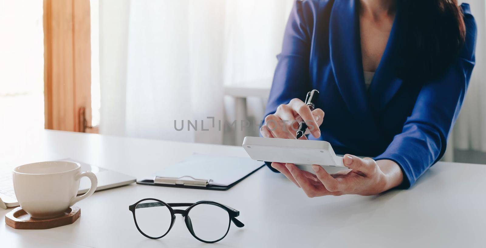 Close up Businesswoman using calculator and laptop for calaulating finance, tax, accounting, statistics and analytic research concept.