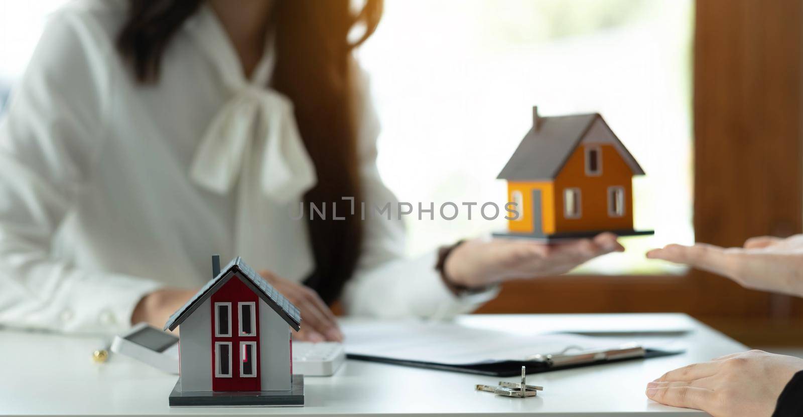 House model with agent and customer discussing for contract to buy, get insurance or loan real estate or property. by wichayada