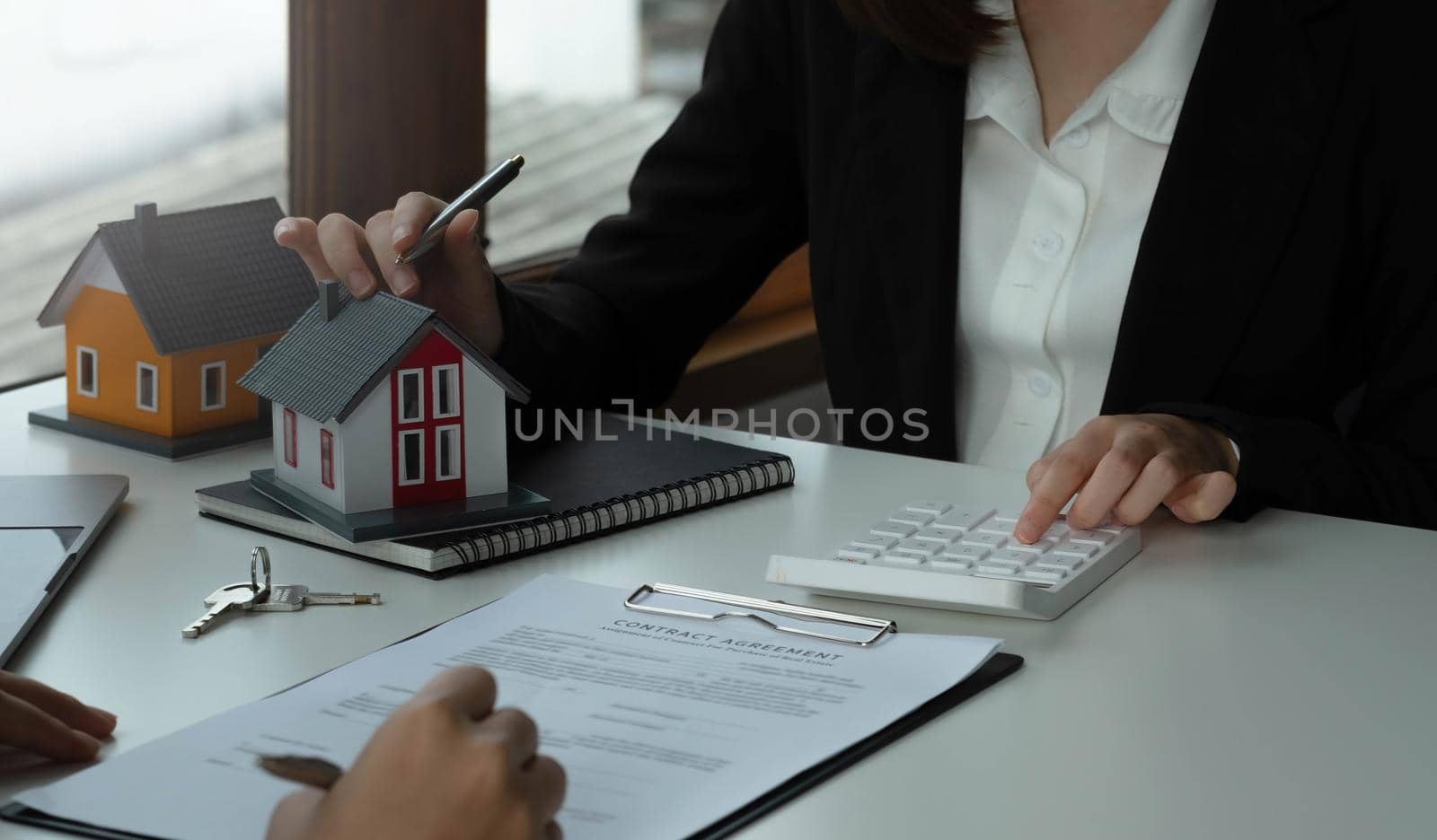 Real Estate concept, Agent holds calculator for present price for loan investment chart graph documents and calculating table payment to customer.