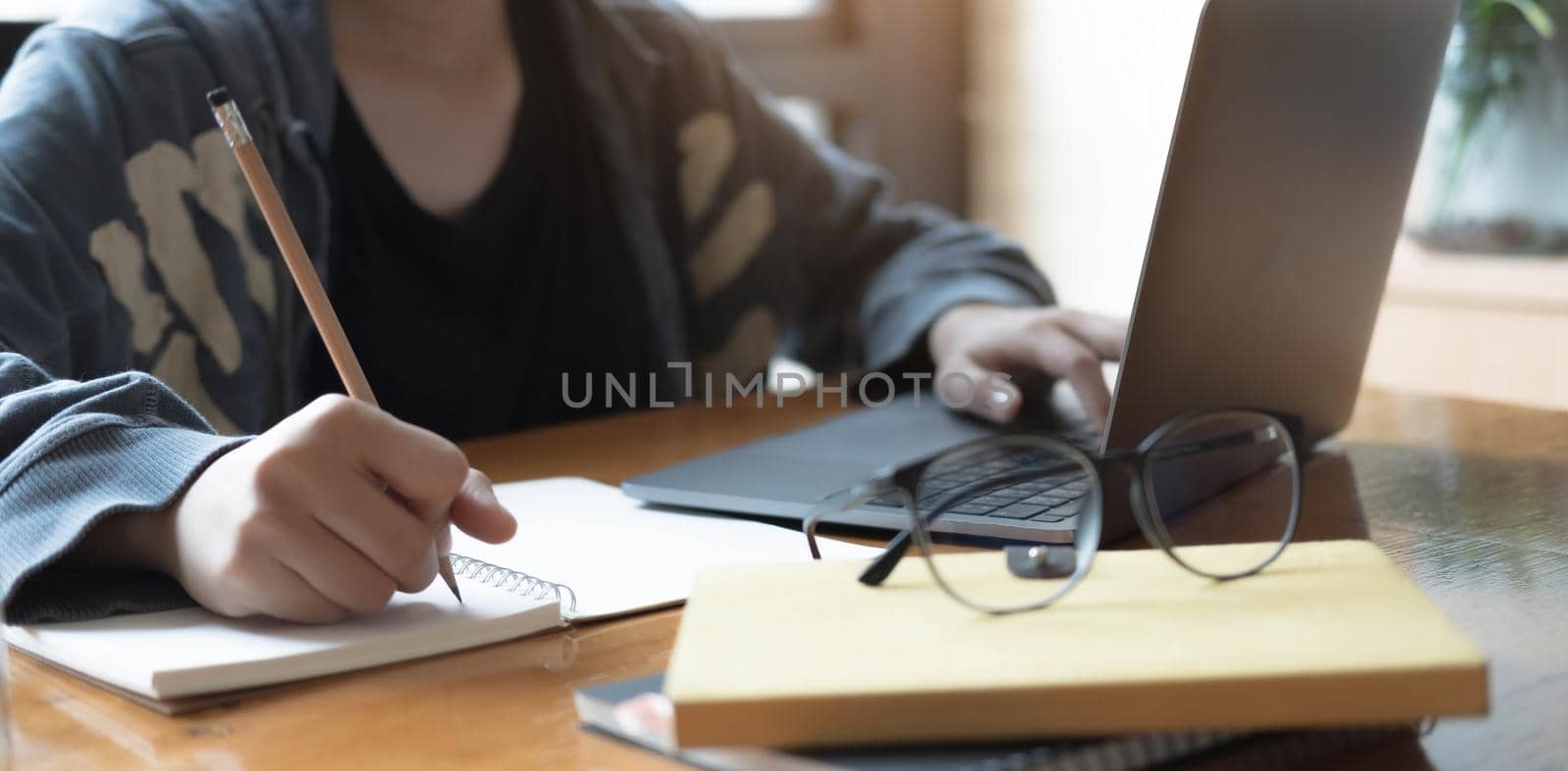 Close up women using laptop and note some data on notepad