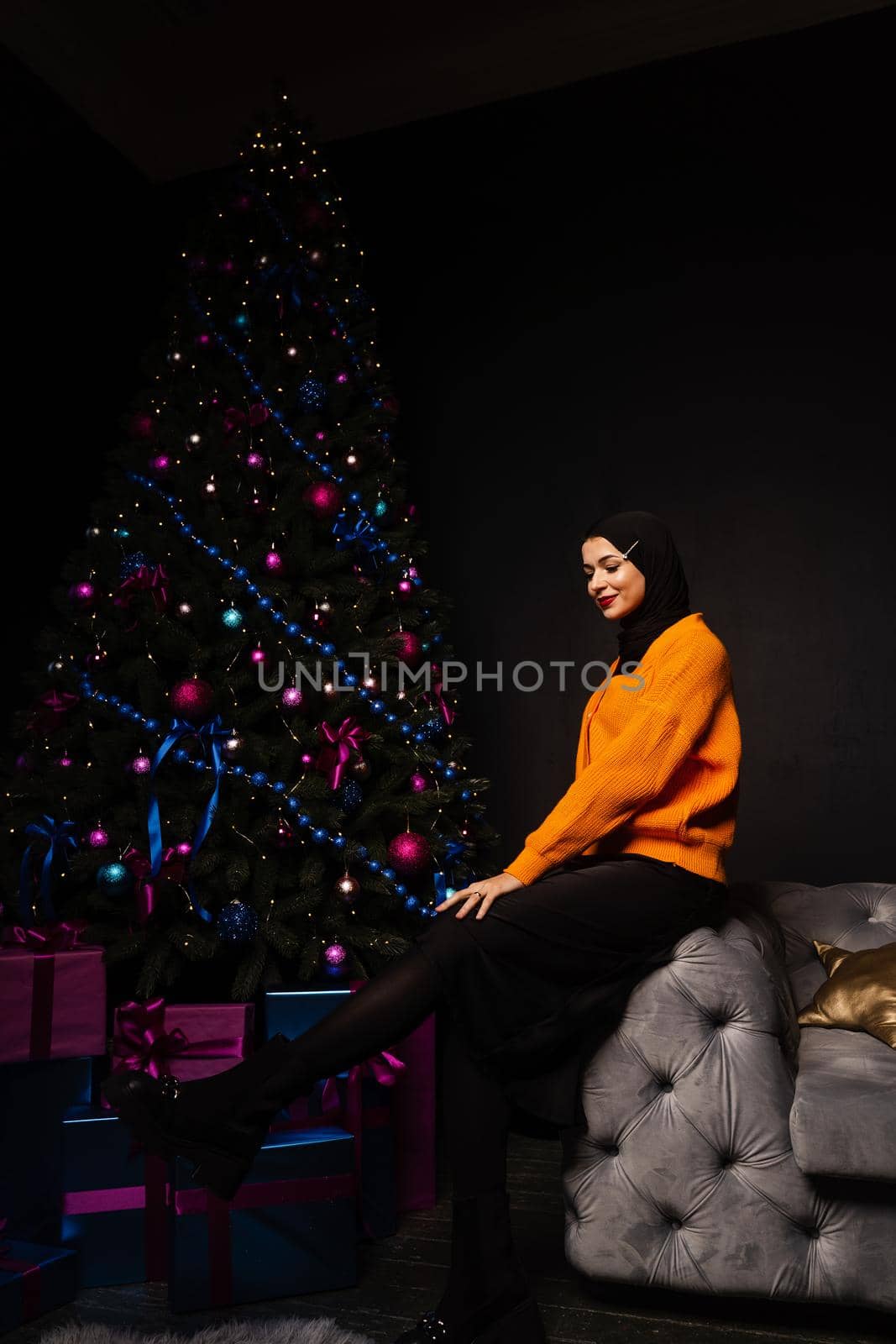 Muslim woman in black hijab near new year tree waiting for celebration of Christmas. Islam religion