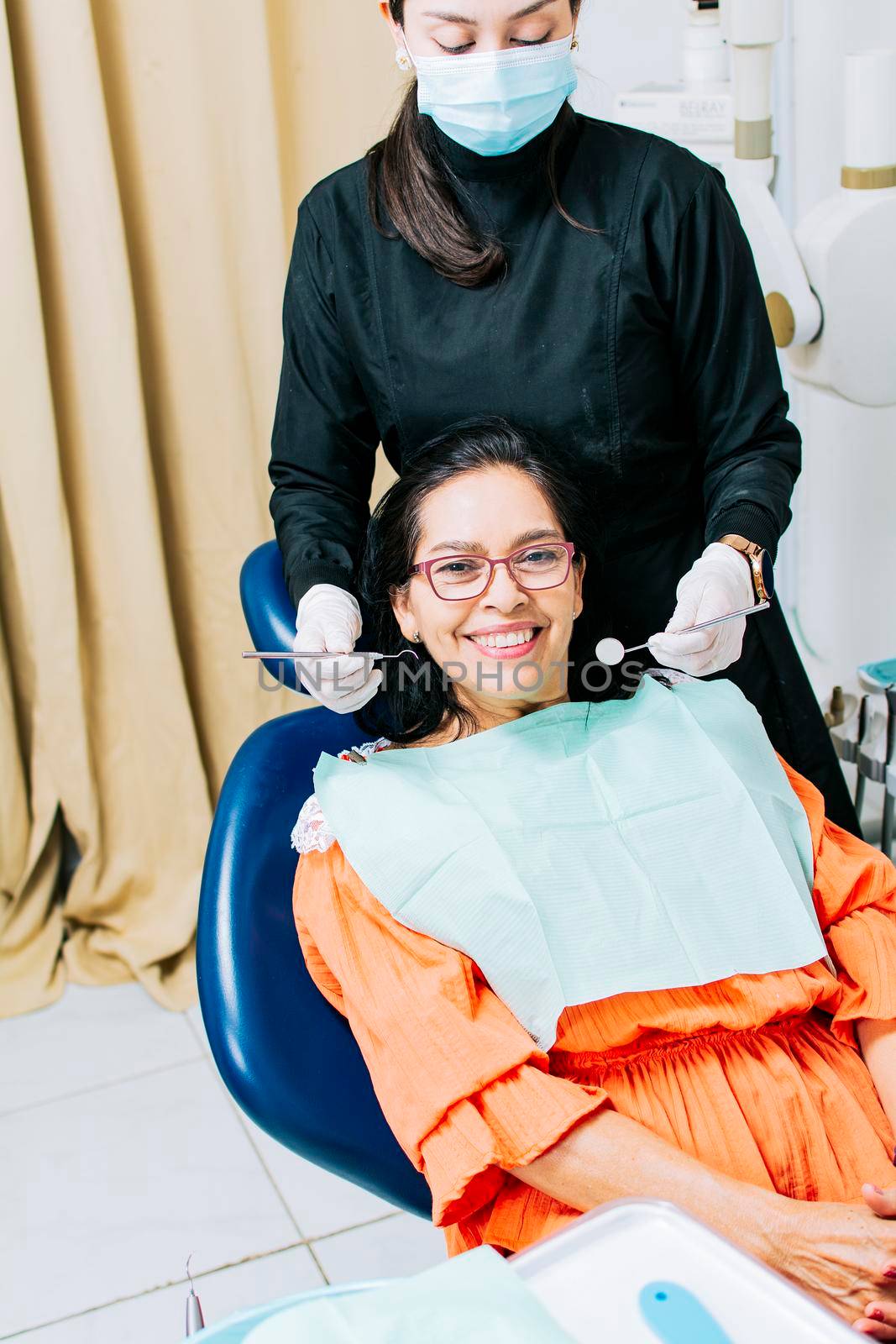 Dentist examining mouth to smiling patient, Female dentist doing root canal to female patient, Female dentist with lying patient, Dentist performing stomatology by isaiphoto