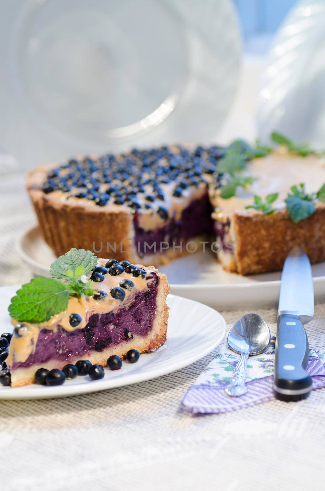 Slice of blueberry pie with mint served with knife and spoon by zimages