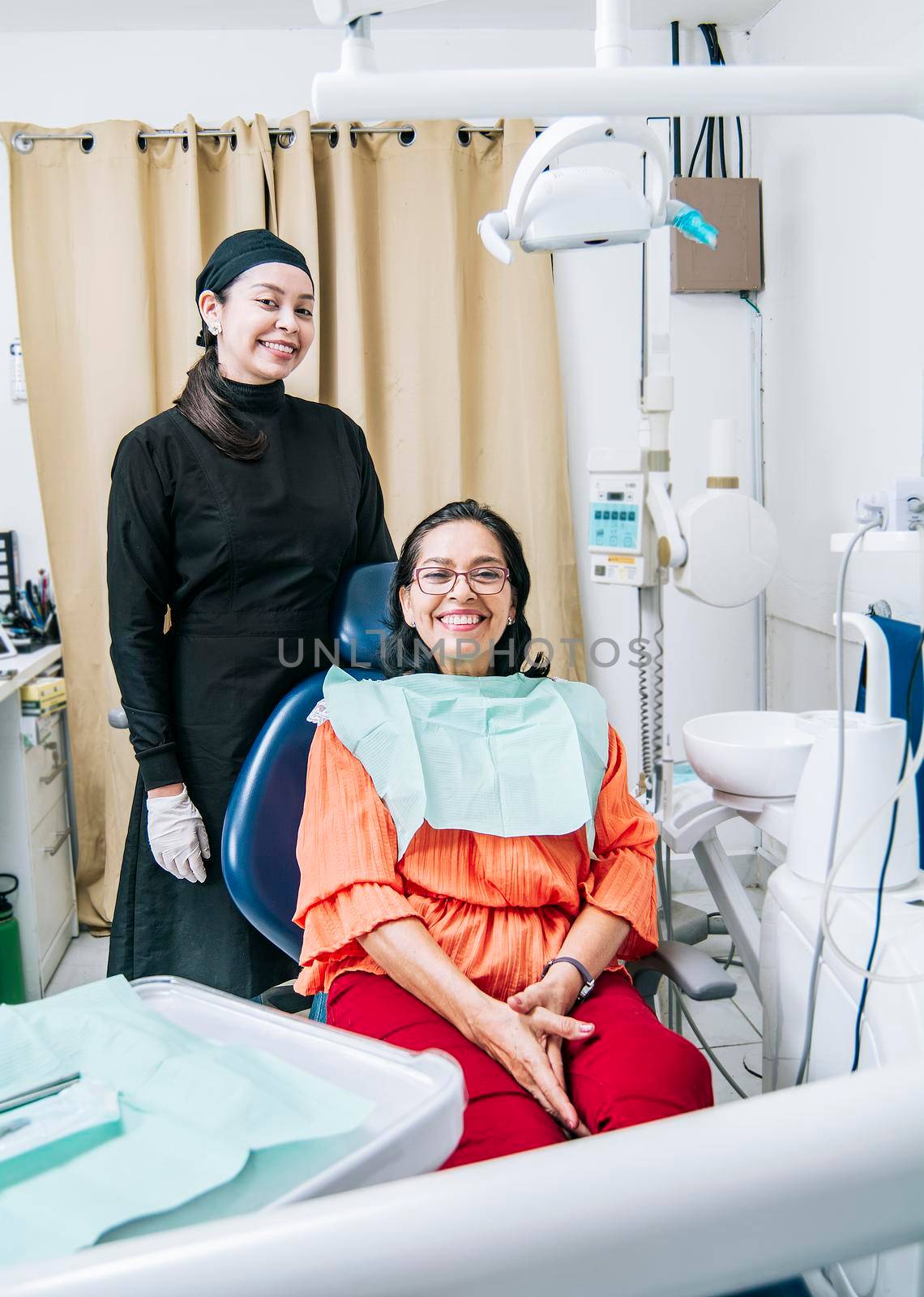 Dentist with patient smiling at camera in office, satisfied dentist and patient smiling at camera, satisfied dentist and patient concept