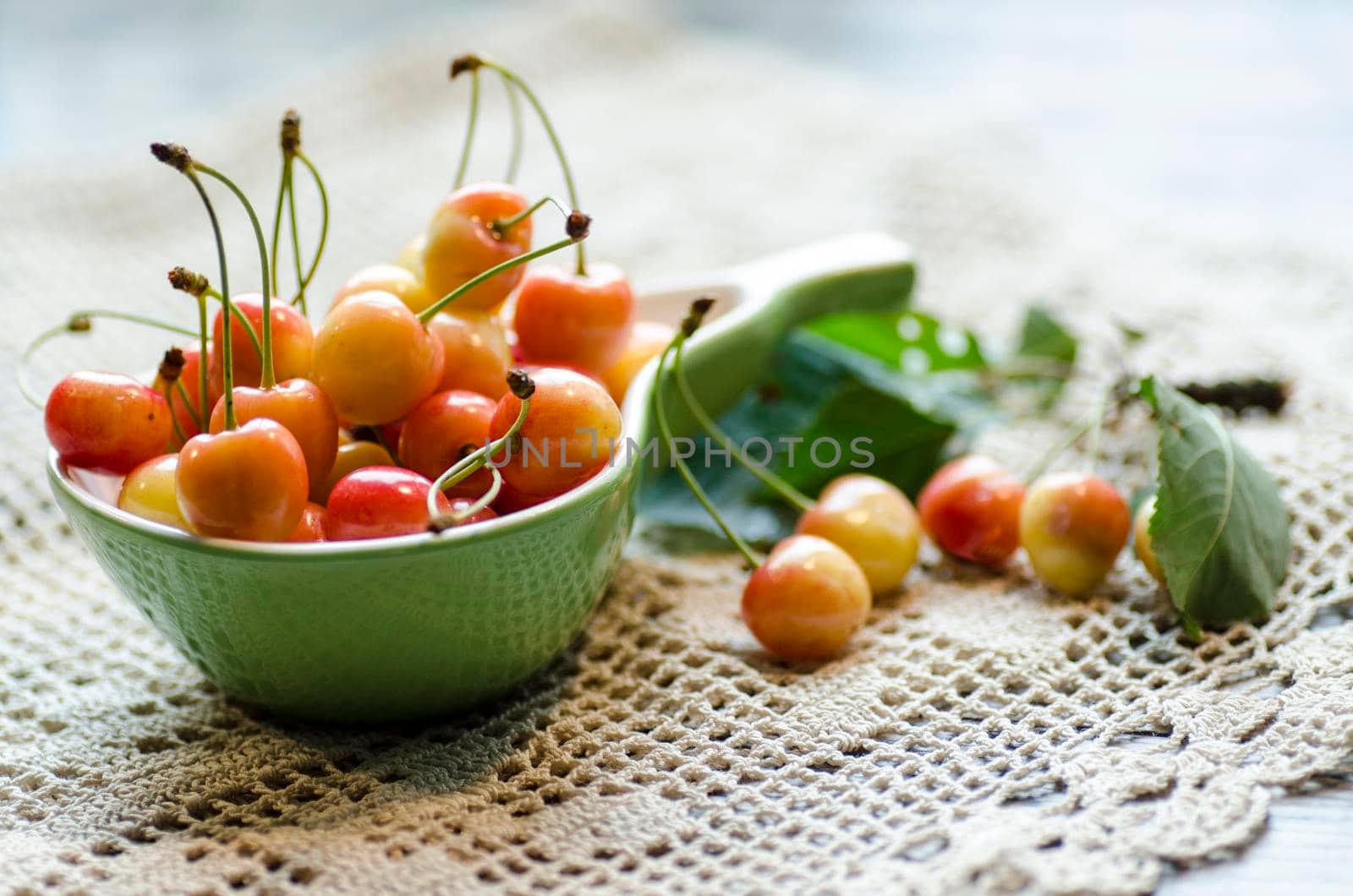 Ripe cherries in the cup on knitted tablecloth