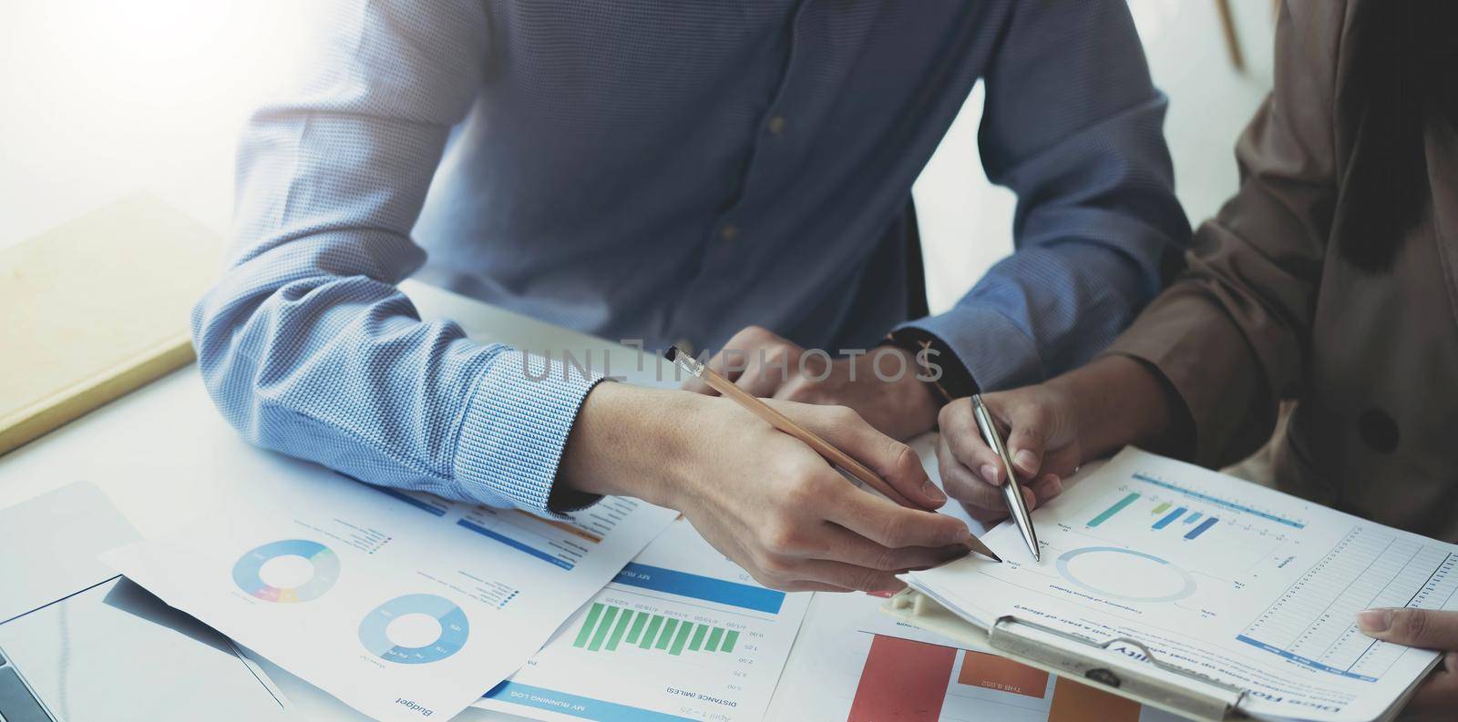 Asian business people meeting new startup project pointing at graph discussion and analysis data charts and graphs.Business finances and accounting concept by wichayada