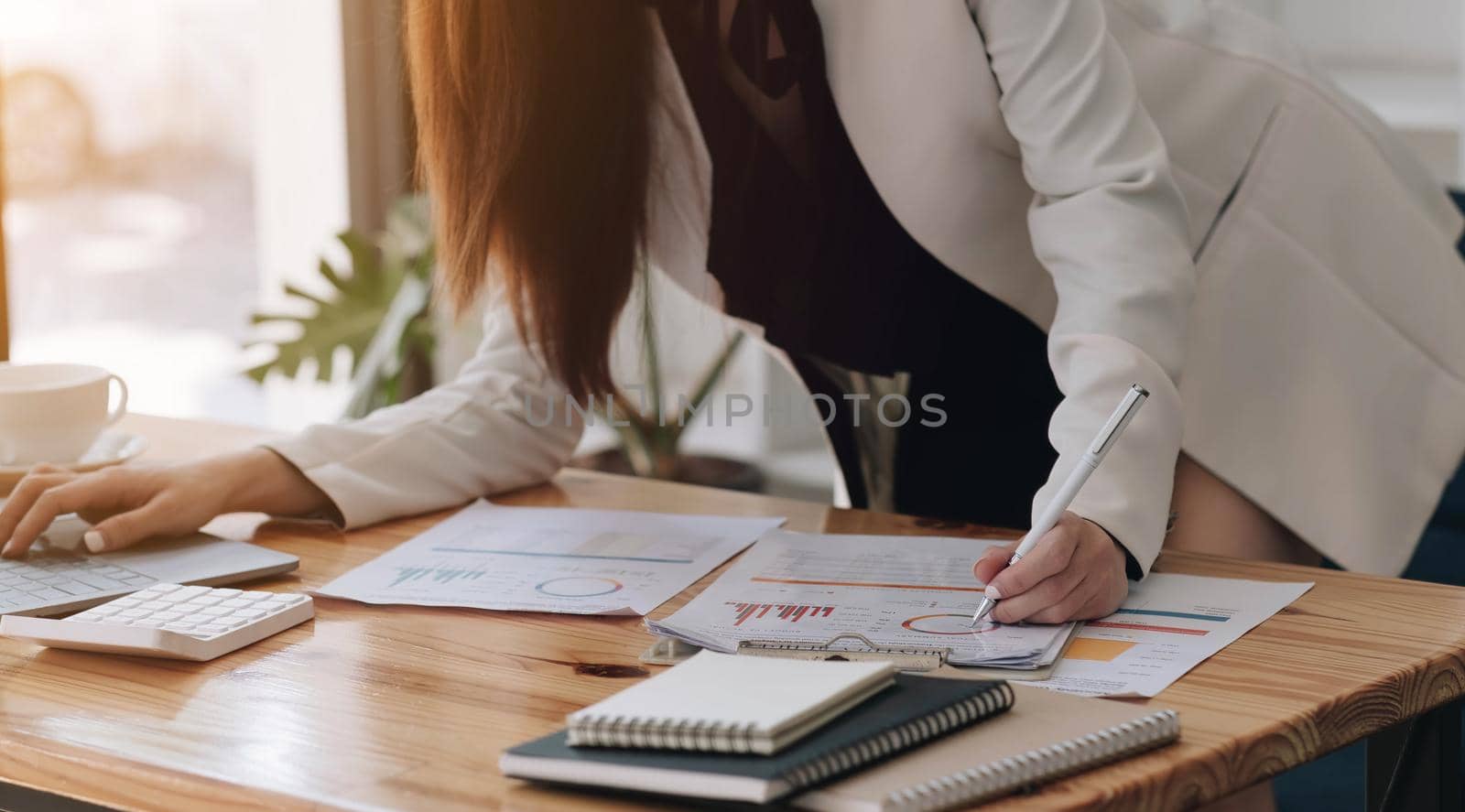 Close up of businesswoman or accountant hand holding pencil working on calculator to calculate financial data report, accountancy document and laptop computer at office, business concept.