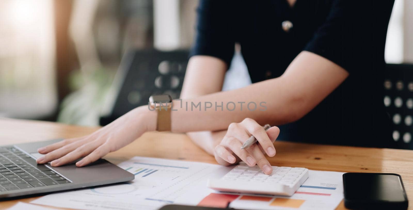 Close up Business woman using calculator and laptop for do math finance on wooden desk in office and business working background, tax, accounting, statistics and analytic research concept.