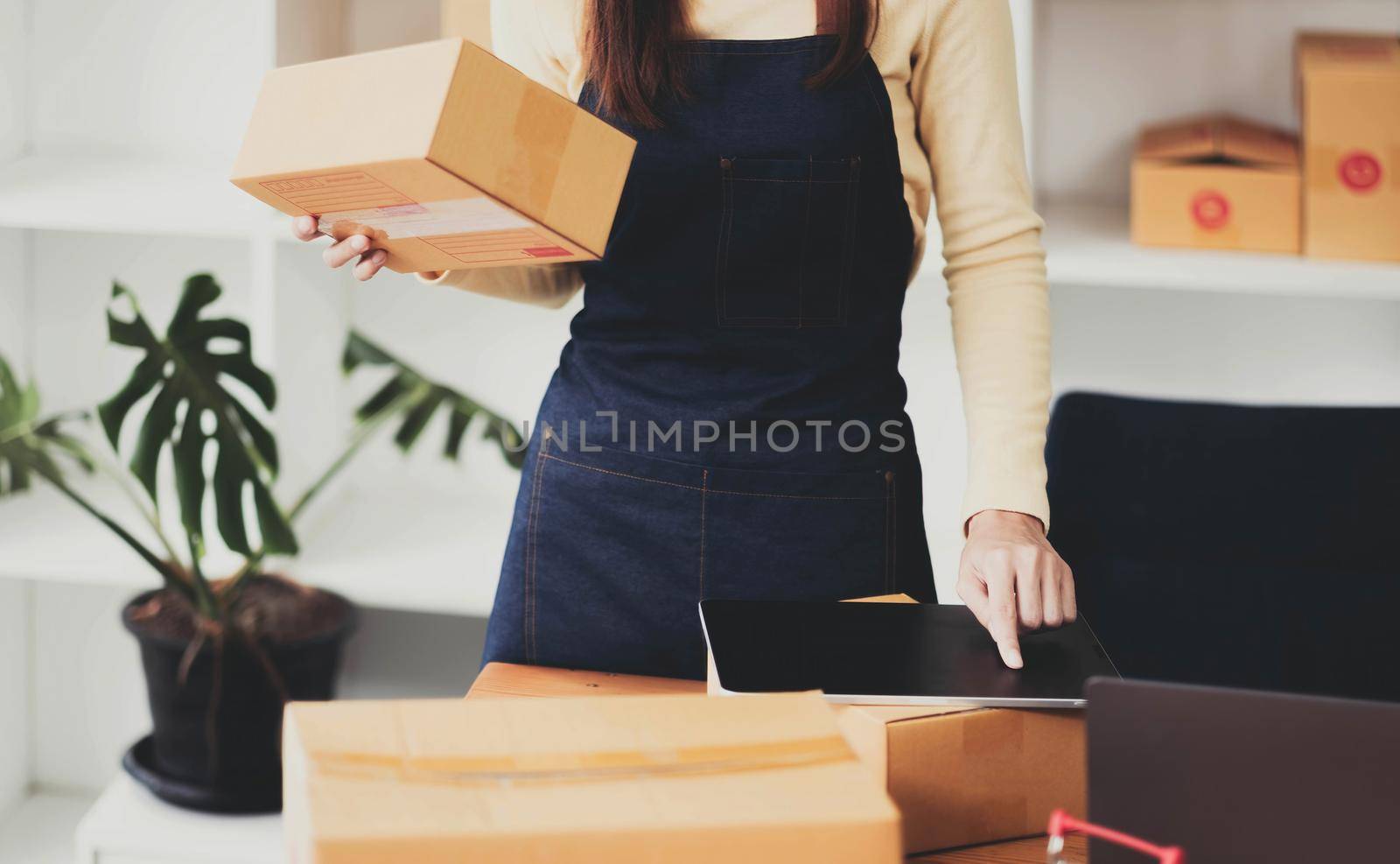 Young asian woman check order for shipping at home, business owner woman start up for business online, SME, Delivery project, woman with Online business or SME concept by wichayada