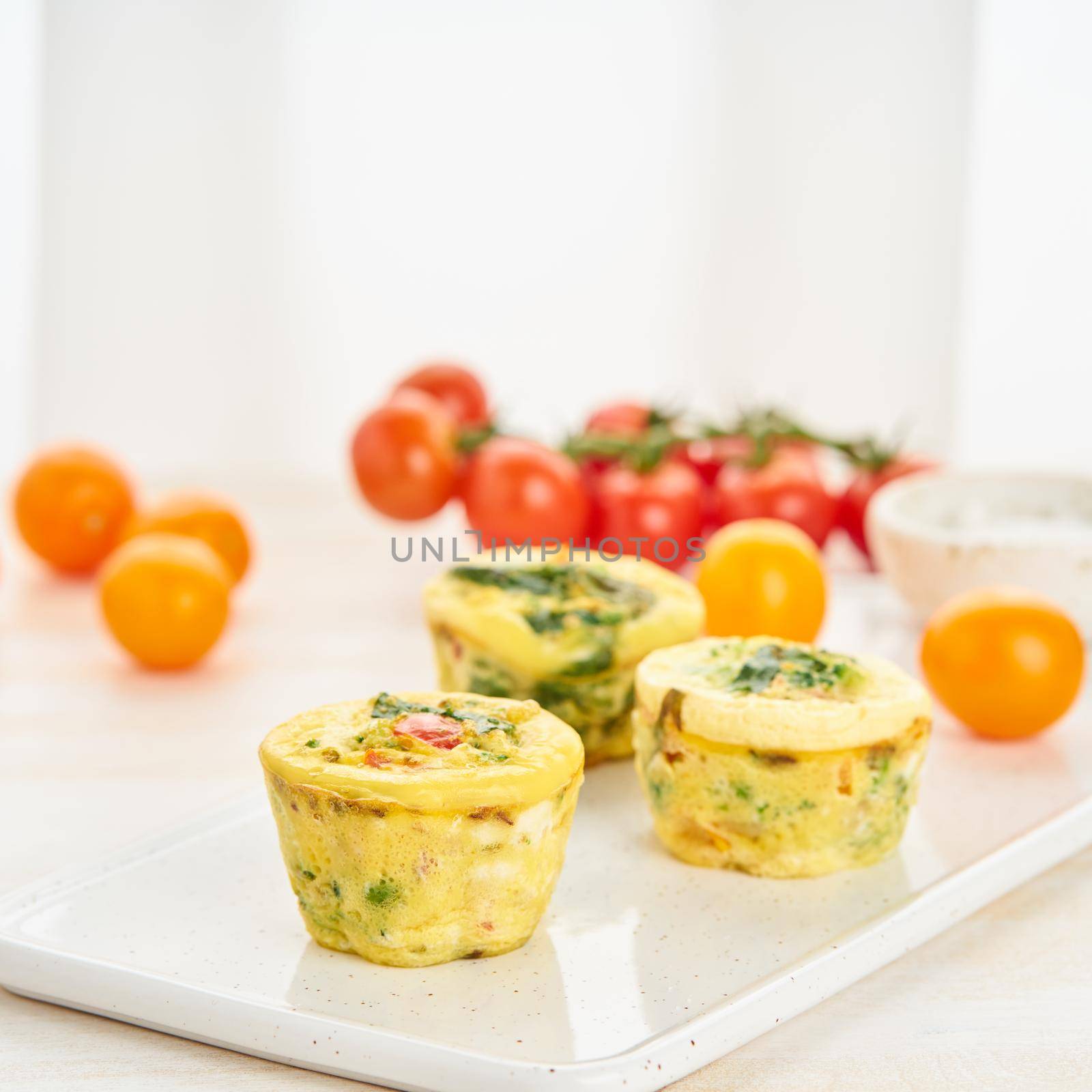 Egg muffins, paleo, keto diet. Omelet with spinach, vegetables, tomatoes baked in small molds by NataBene