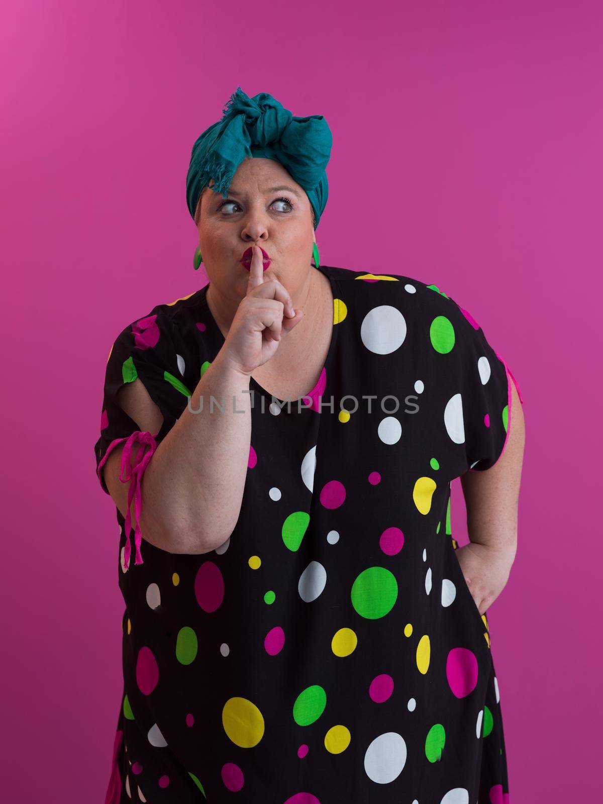 Plus size sexy model woman with trendy makeup, fashionable blonde in black short dress posing at the pink background in studio. High quality photo