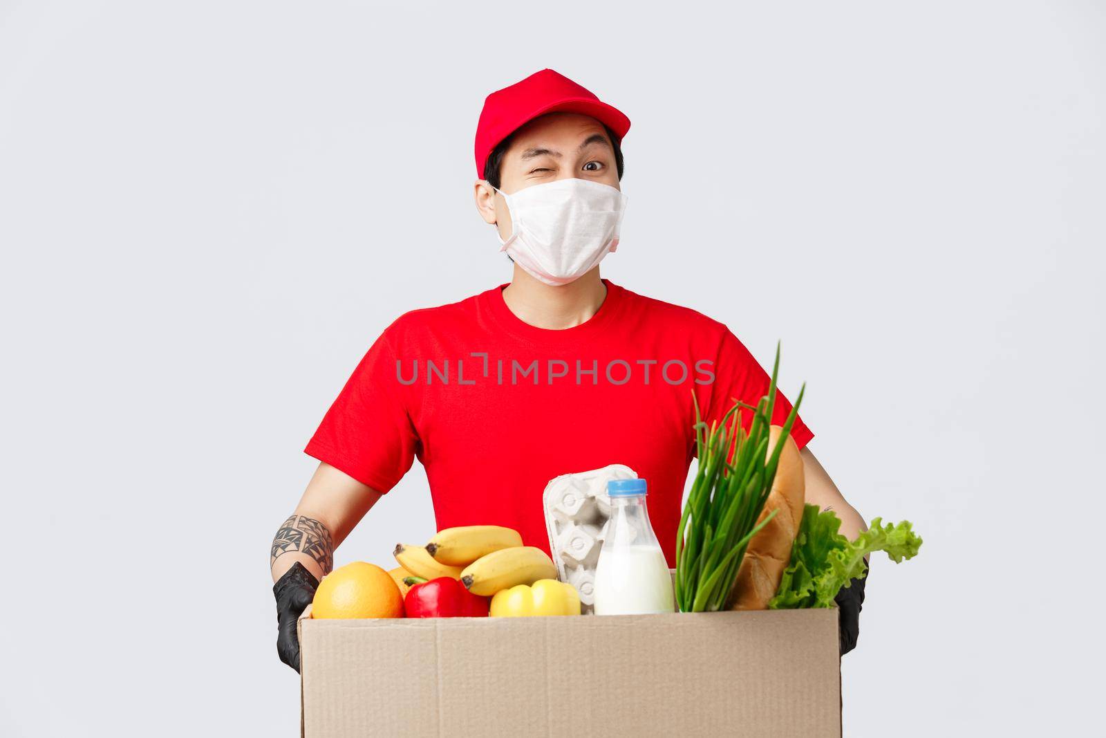 Online shopping, food delivery and coronavirus pandemic concept. Cheerful asian delivery guy bring customer online shop order, courier holding package with fresh groceries, employee deliver products.