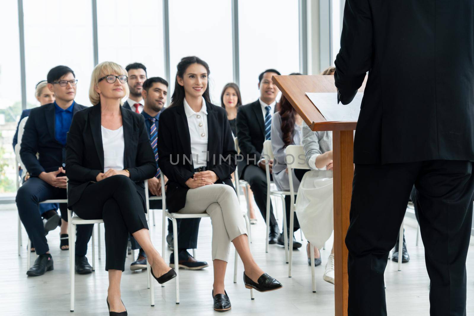 Group of business people meeting in a seminar conference . Audience listening to instructor in employee education training session . Office worker community summit forum with expert speaker .