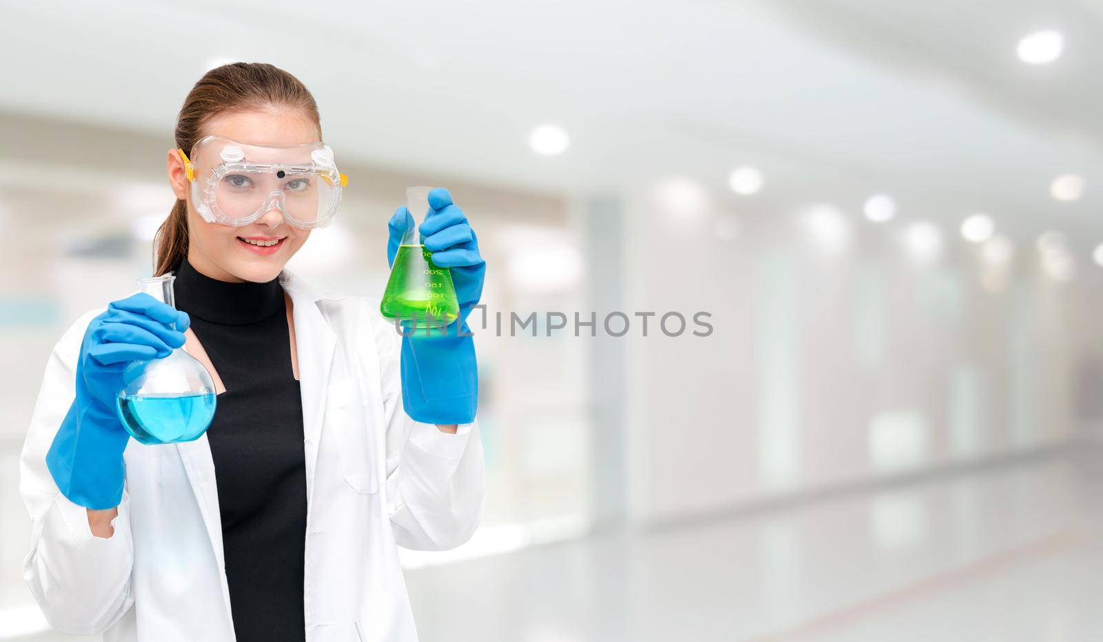 Portrait of young happy scientist or chemist holding test tube in laboratory. Chemical or medical technology research and development concept.