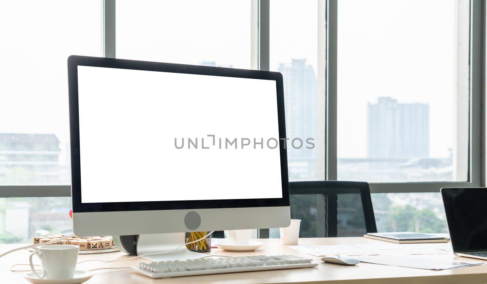 Empty computer monitor screen for design mock up template in modern small office interior or home office. Stylish workplace for creative occupation.
