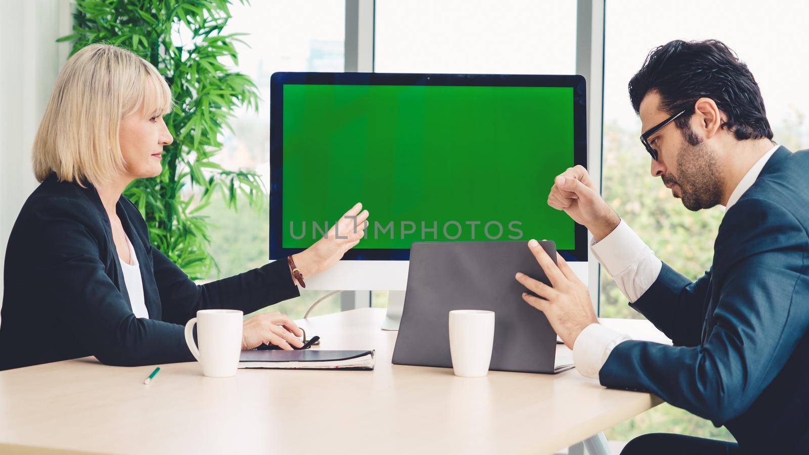 Business people in the conference room with green screen chroma key TV or computer on the office table. Diverse group of businessman and businesswoman in meeting on video conference call .