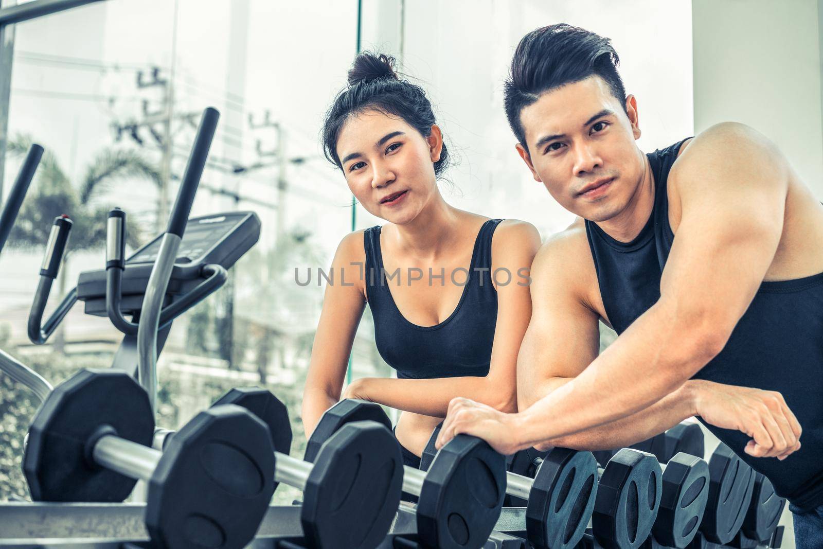 Healthy man and woman doing weight training in gym fitness center. Bodybuilding concept.
