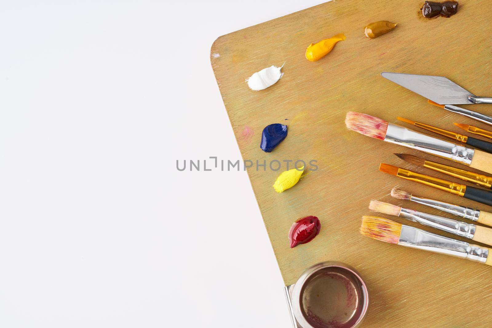 palette with paints and brushes for oil painting on a white background, copy space