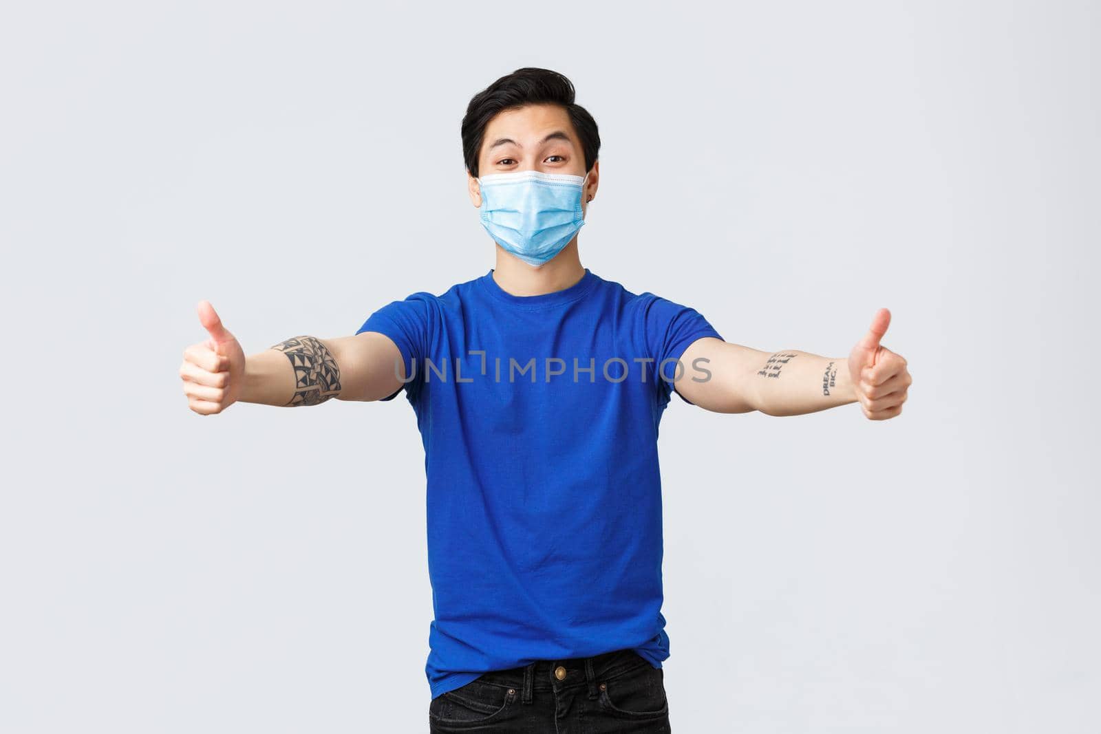 Different emotions, social distancing, self-quarantine on covid-19 and lifestyle concept. Friendly handsome asian guy in medical mask reaching hands for hug, embraces, or cuddles.