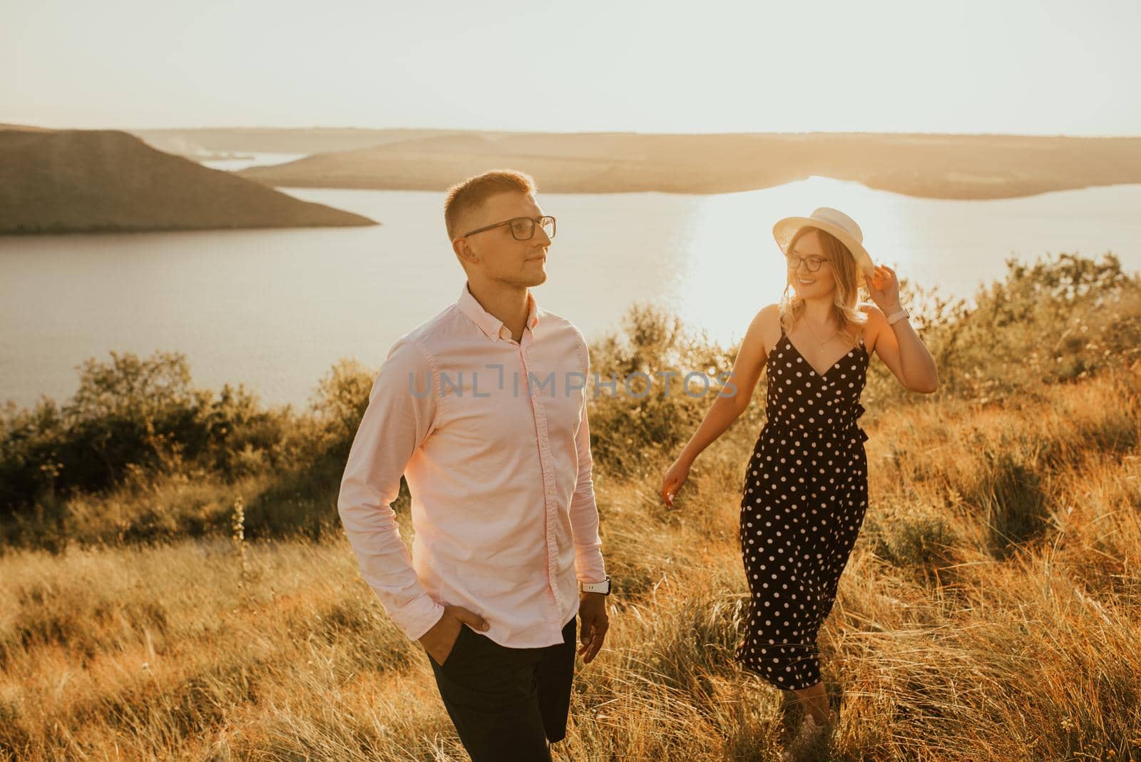 woman behind man in rays of setting sun in summer near lake