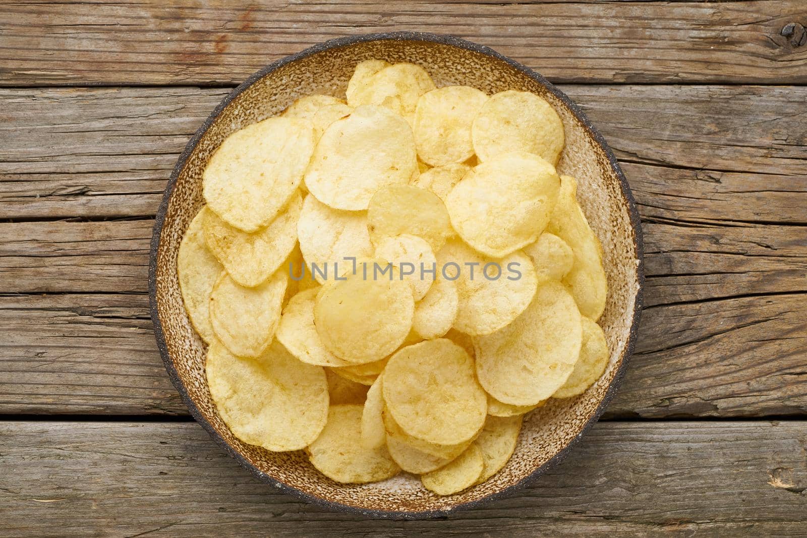 crisp in bowl, wooden background, top view