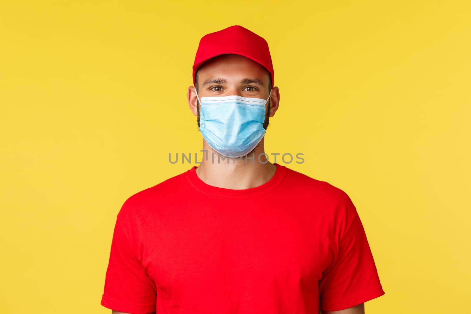 Covid-19, delivery orders, shopping, contactless payment and social distancing concept. Pleasant young nice male employee in red uniform cap and t-shirt, pleased help customer, wear medical mask.