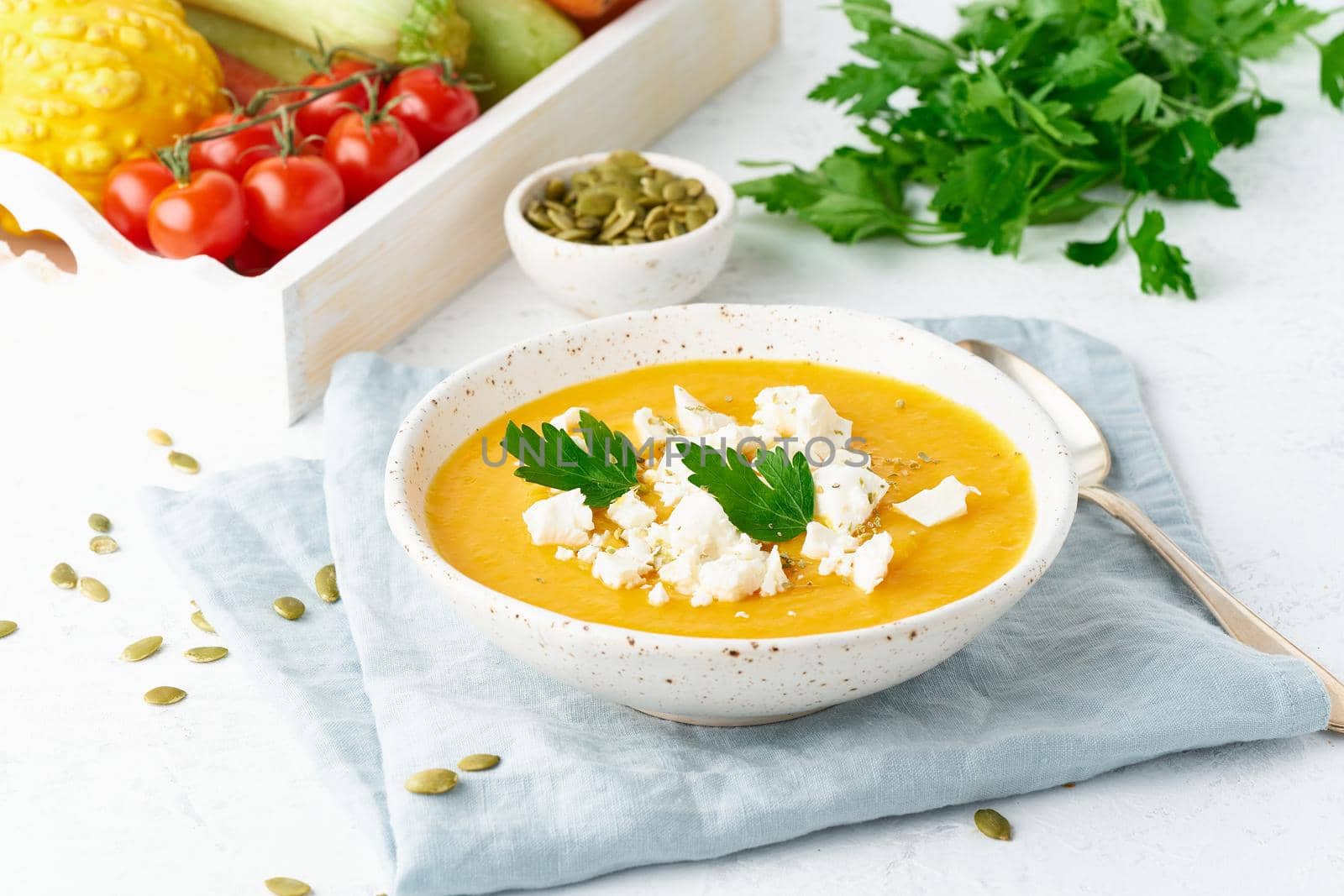 Pumpkin cream soup with feta cheese, autumn homemade food, white background, closeup seasonal vegeterian dish