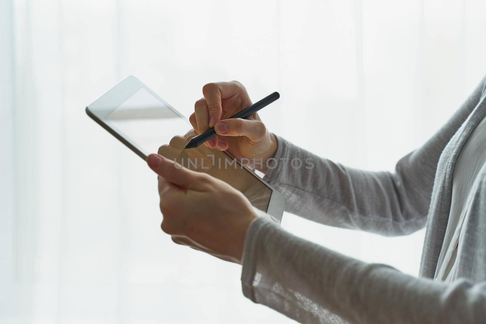 Woman holding tablet and writing on it, person with device side view closup by NataBene