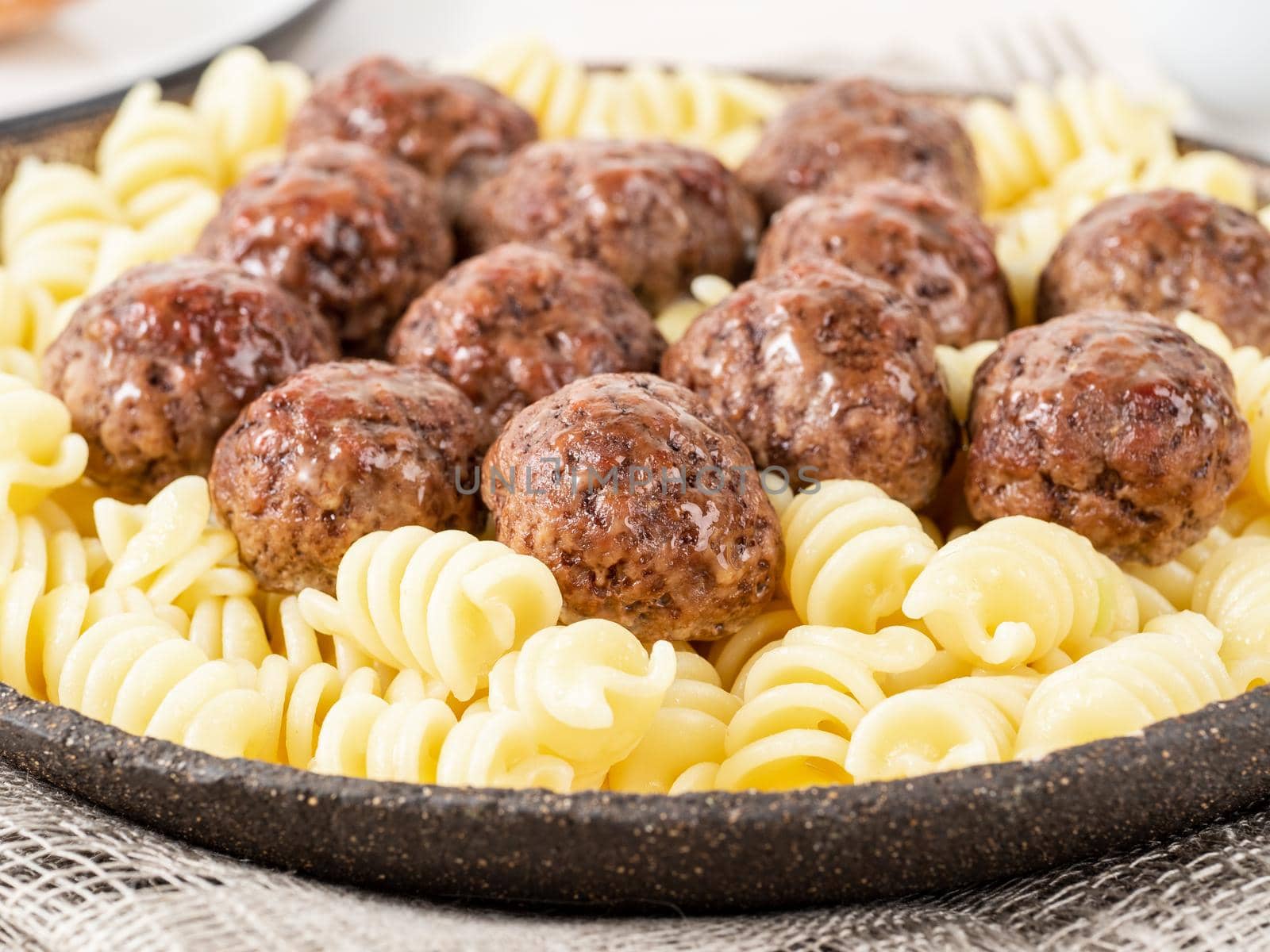 Swedish meatballs with fusilli paste on white wooden table, side view