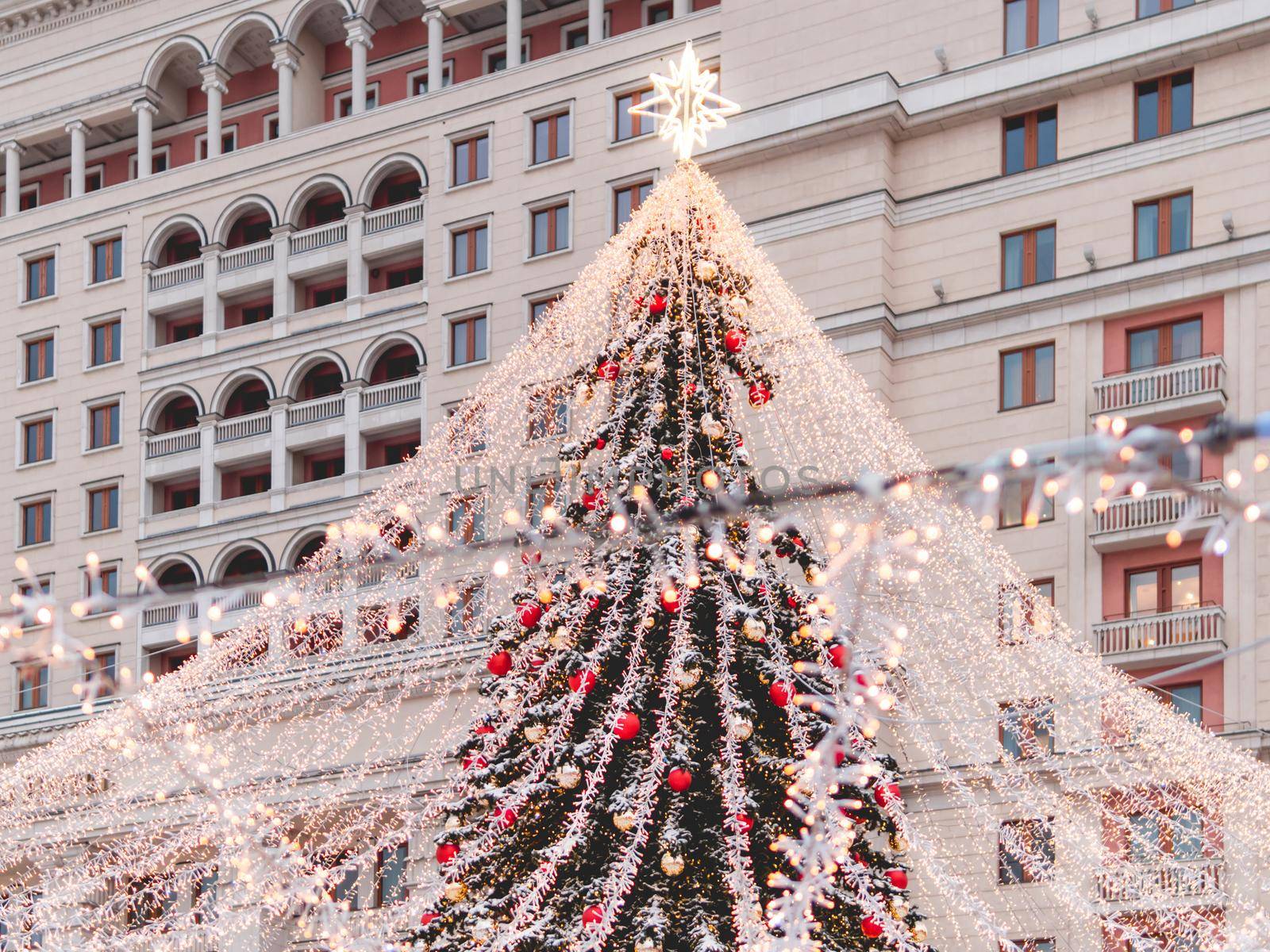 Christmas tree, decorated with light bulbs and bright red balls. Outdoor decorations on fir tree for New Year celebration. Moscow, Russia.