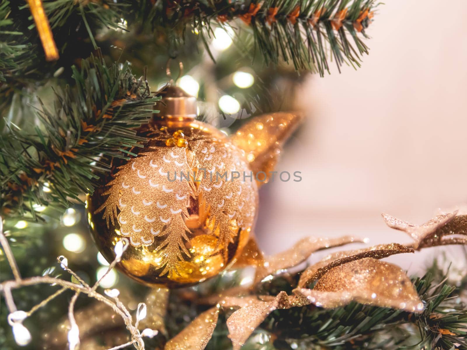 Christmas tree with golden decorations. Fir tree decorated with light bulbs and balls for New Year celebration. Copy space.