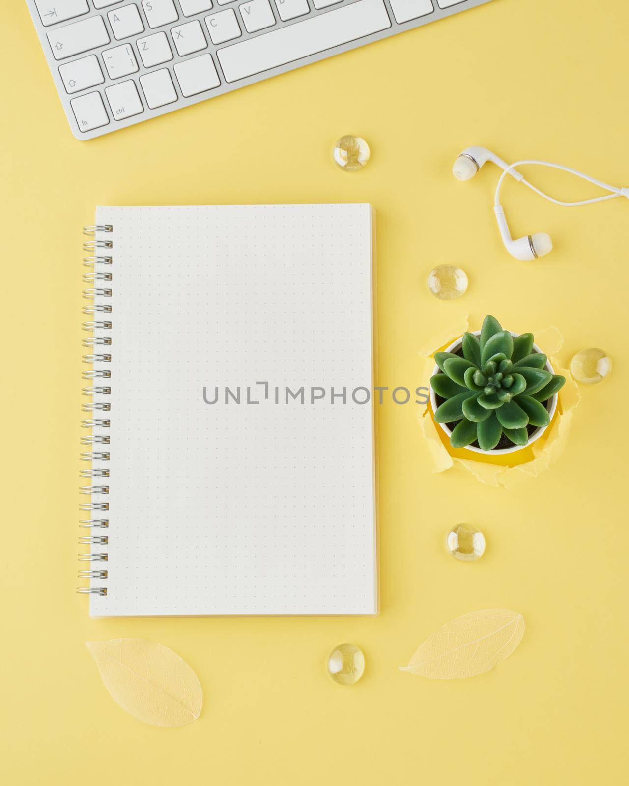 Blank notepad page in bullet journal on bright yellow office desktop. Top view of a modern bright table with notebook, minimalism. Mock up, copy space, concept for diary, vertical