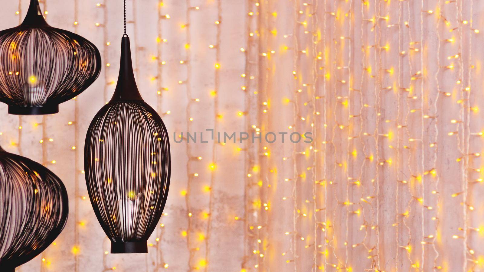 Black ethnic lanterns on background with light bulbs. Eastern lamps on festive Ramadan background. Horizontal banner with copy space.