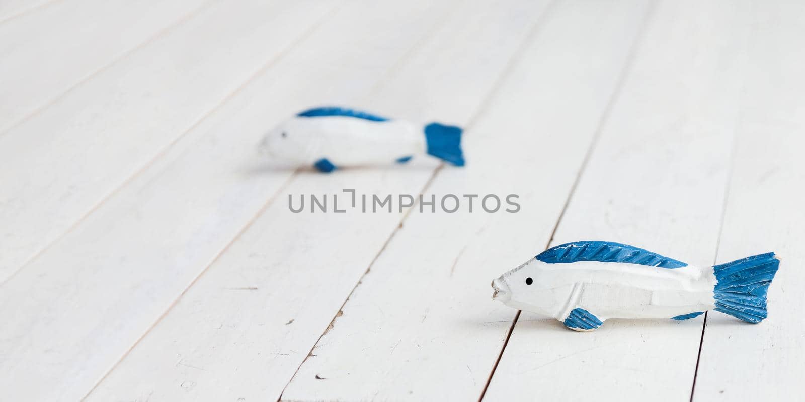 Two wooden fishes on floor. Shabby blue and white handmade toys for children. Horizontal banner with copy space.