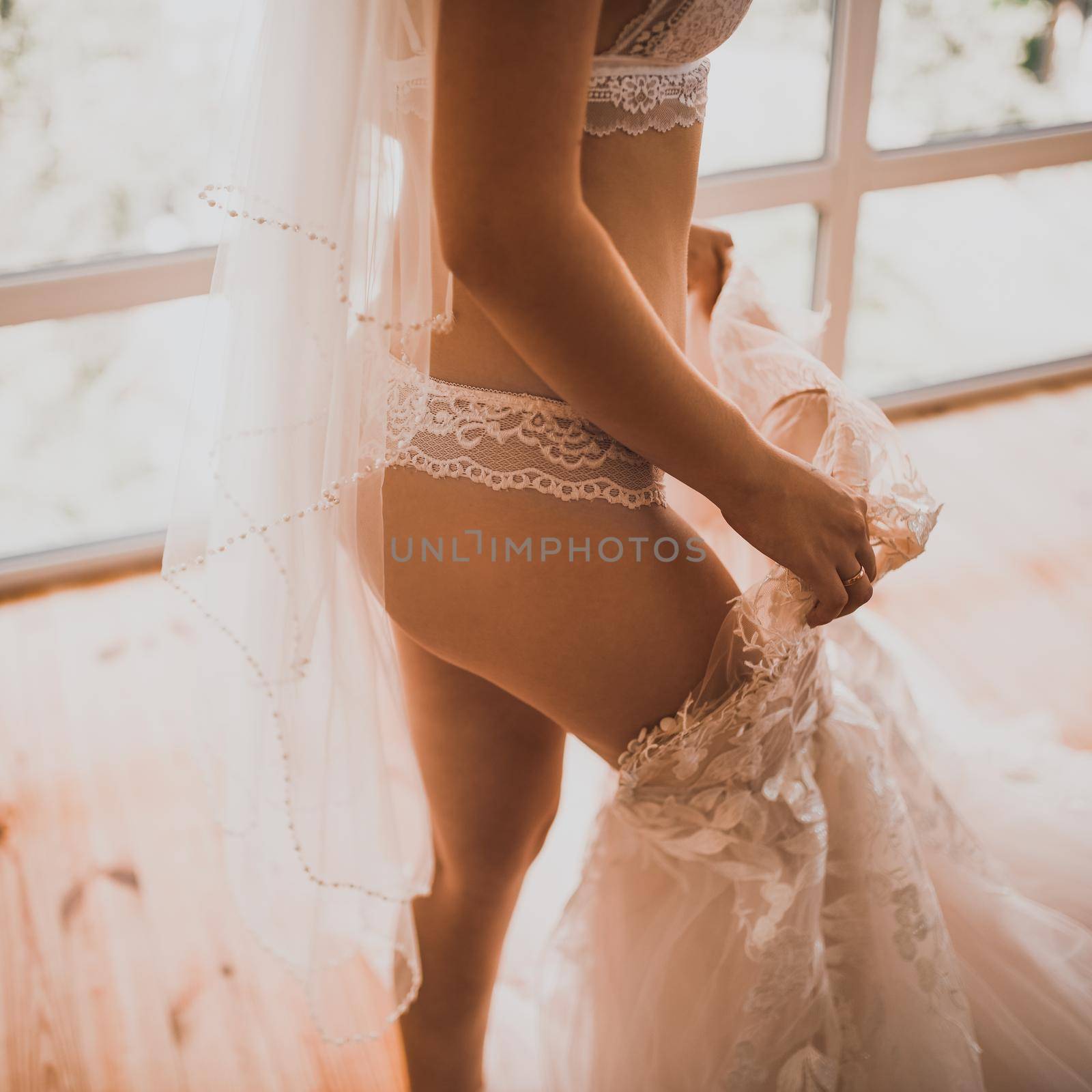 European skinny bride in lingerie puts on a wedding dress by AndriiDrachuk