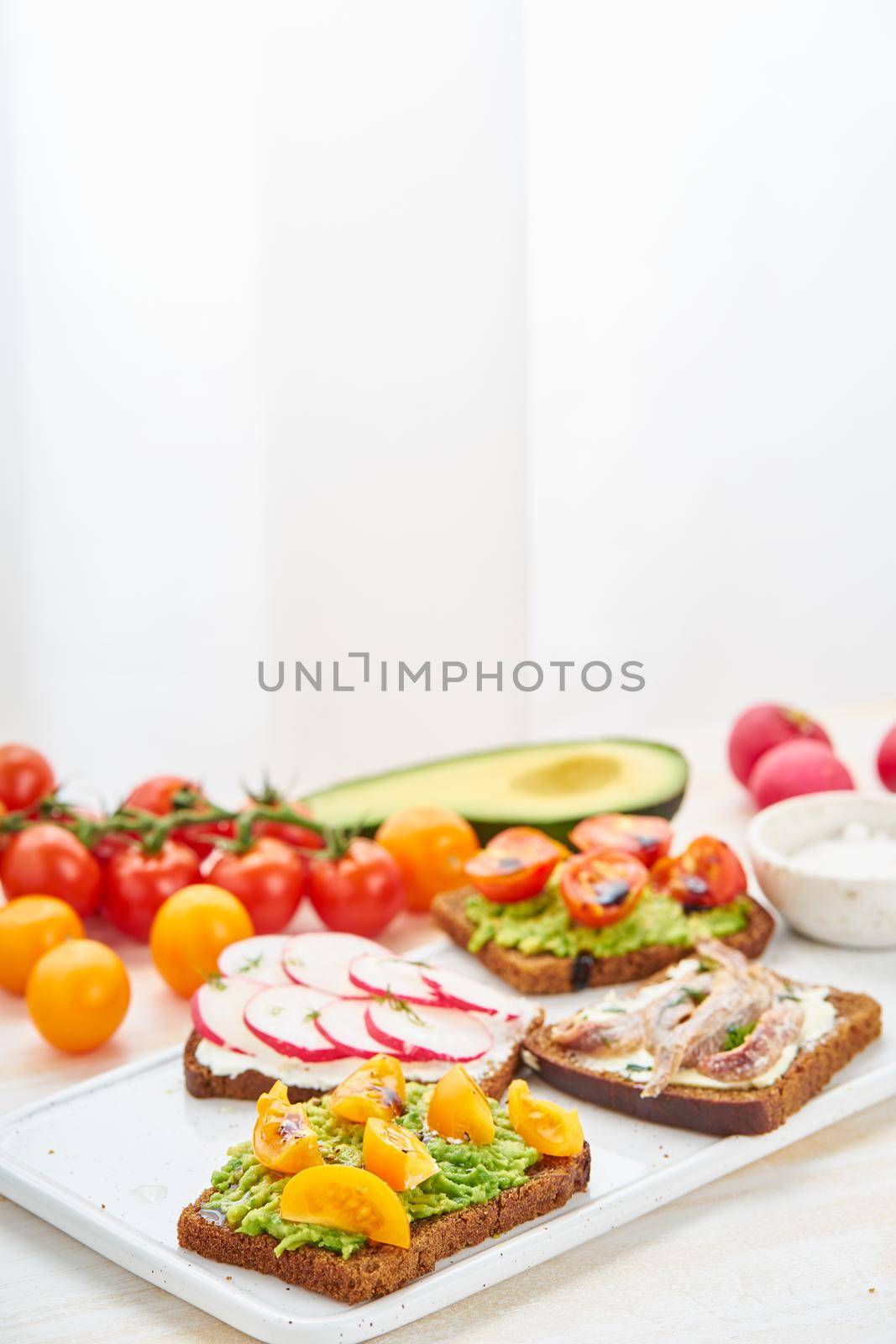 Set of smorrebrods with fish, anchovies, avocado, tomatoes, radish. by NataBene