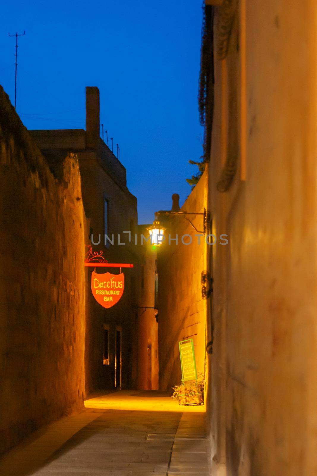 MDINA, MALTA - February 19, 2010. Illuminated narrow streets with cafes and restaurants. Night view on buildings and wall decorations of ancient town. by aksenovko