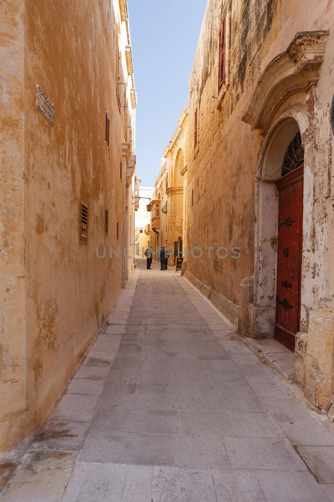 MDINA, MALTA - February 18, 2010. Local old men on narrow street of Mdina, old capital of Malta. Stone buildings with old fashioned doors and balconies.