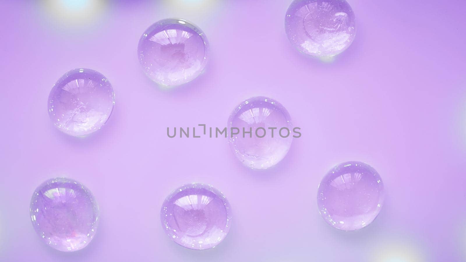 Abstract glass drops beads on a neon purple background, copy space