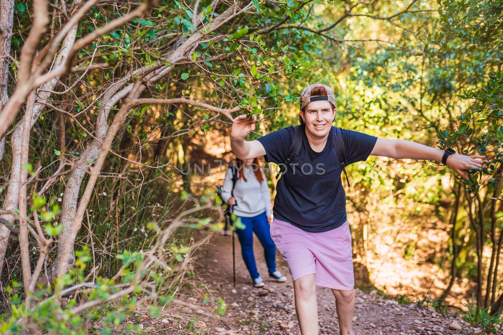 two young women friends hiking amateur, en route on a forest trail. hikers reaching the top. people on a trip. by CatPhotography