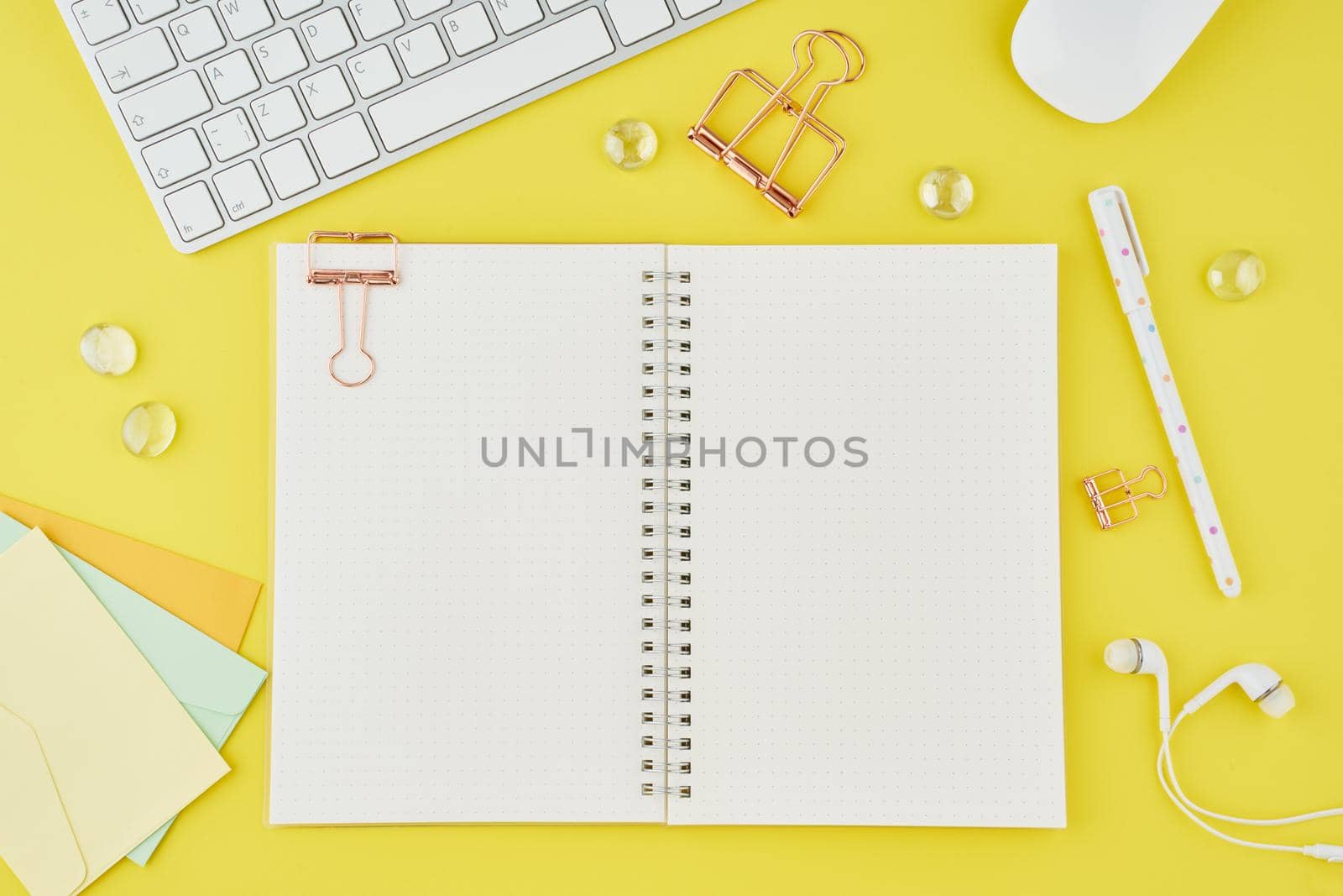 Blank notepad page in bullet journal on bright yellow office desktop. Top view of a modern bright table with notebook, stationery. Mock up, copy space, concept for diary