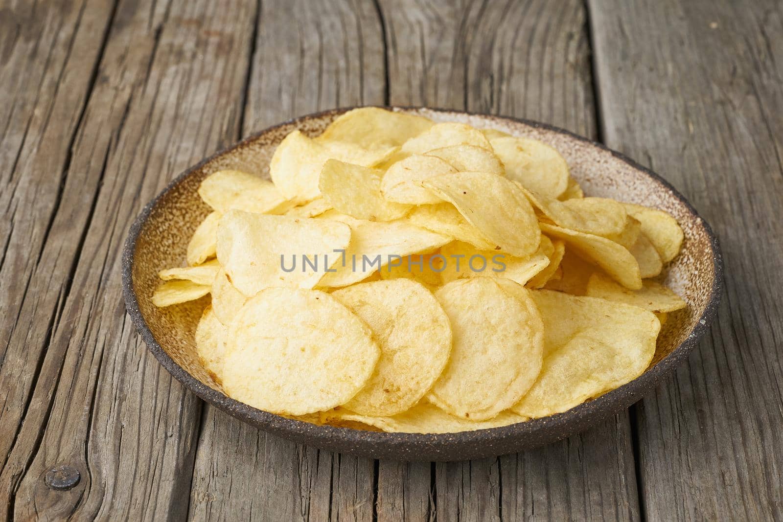 crisp in bowl, wooden background, closeup